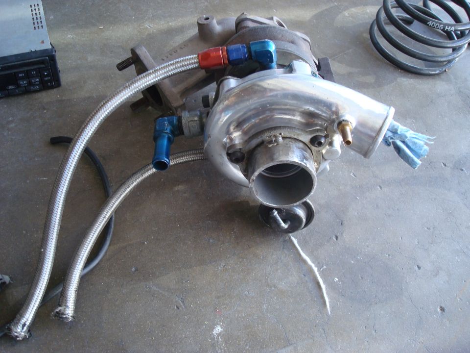 Polished turbocharger with braided oil lines on a garage floor