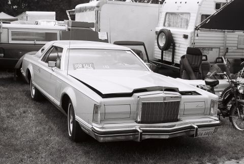 1973 Ford Ranchero - A white 1977 Lincoln Continental Mark V is for sale, parked next to trailers and a motorcycle.