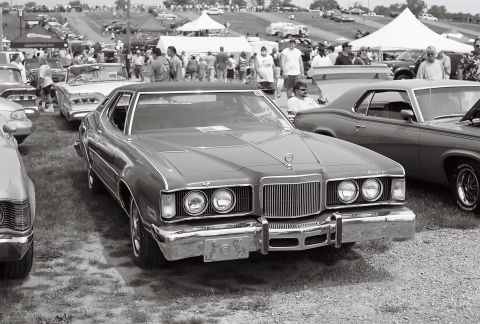 1973 Ford Ranchero - A 1974 Mercury Cougar XR-7 is parked at an outdoor car show with other vehicles and spectators in the background.