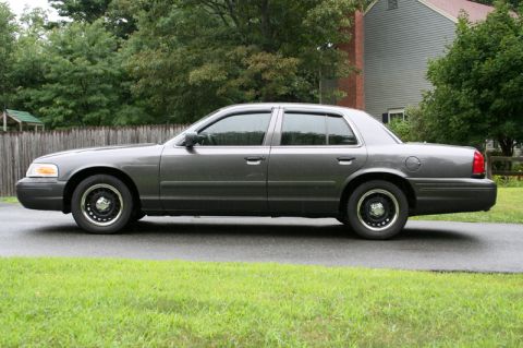 2000 Ford Crown Victoria - This gray 2000 Ford Crown Victoria sedan is shown from the side with tinted windows and black steel wheels.