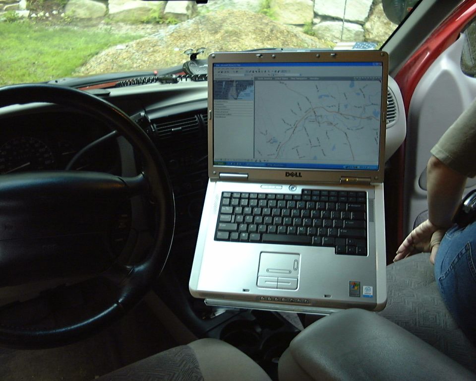 Dell laptop on a mount inside a vehicle showing map software, steering wheel at left