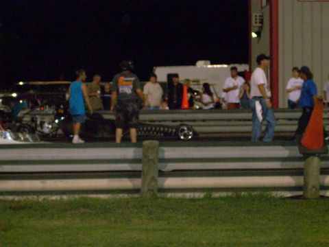 1991 Ford Mustang - Nighttime drag racing event with spectators and a race car on the track.