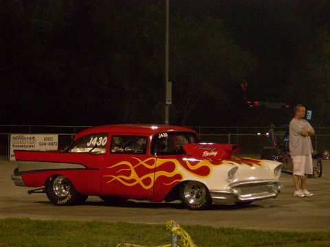 1991 Ford Mustang - A custom drag car with flame decals sits on the track at night, with a spectator watching.