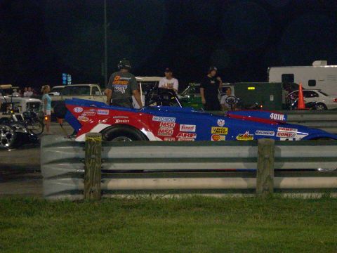 1991 Ford Mustang - A drag car with numerous sponsor decals is positioned on a track.