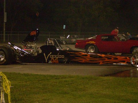 1991 Ford Mustang - Drag racing at night with a dragster and a red muscle car on the track.