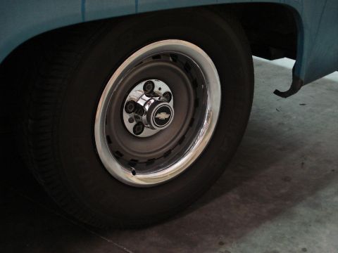 1979 Chevrolet C/K Pickup - A close-up view of a vehicle's wheel, showing the tire, rim, and a Chevrolet emblem on the hubcap.