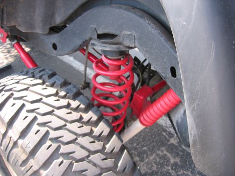 2001 Jeep Wrangler - Close-up view of the suspension system on a 2001 Jeep Wrangler, highlighting the red coil springs and off-road tire.