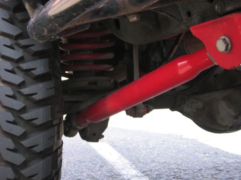 2001 Jeep Wrangler - The image shows a close-up view of the suspension system of a vehicle, red-painted components and a large tire.