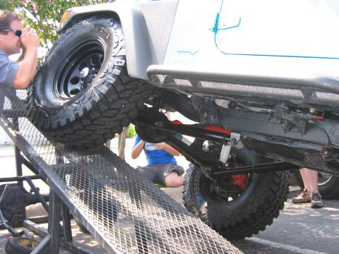 2001 Jeep Wrangler - A person photographs the underside of a Jeep Wrangler as it is driven onto a ramp, highlighting its off-road tires and suspension.