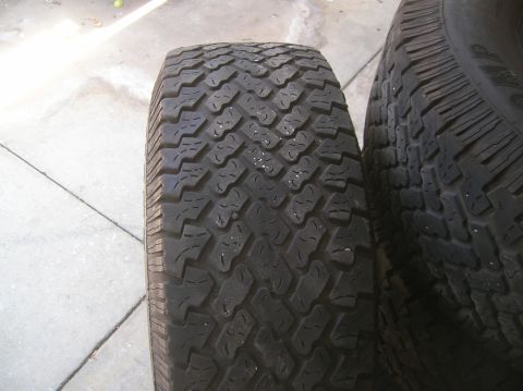 1985 Ford Bronco - Two tires with aggressive tread patterns are shown side-by-side on a concrete surface.