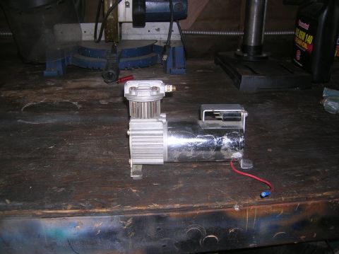 1985 Ford Bronco - A chrome air compressor with silver fins and a red wire is shown on a workbench.