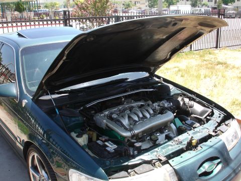 1993 Ford Taurus - The engine bay of a dark green sedan is displayed with the hood and sunroof open.