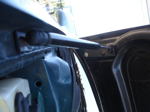 1993 Ford Taurus - Close-up of a hood strut assembly, showing its mounting points on the vehicle's body and hood.