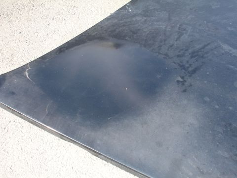 1991 Ford Taurus - A close-up of a dark-colored car hood shows wear and tear.