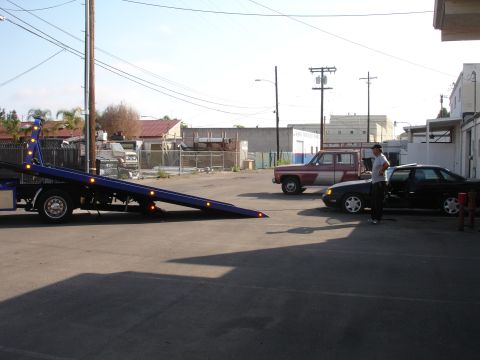 1991 Ford Taurus - A 1991 Ford Taurus is parked in a lot with a tow truck and a pickup truck nearby.