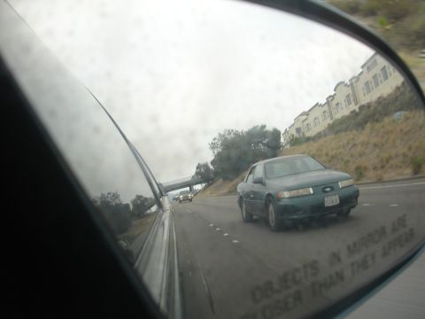 1991 Ford Taurus - A green 1991 Ford Taurus is seen in the side mirror while driving on the highway.