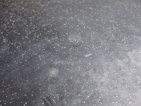 1991 Ford Taurus - A close-up view of a textured gray surface covered in numerous small, reflective white specks.