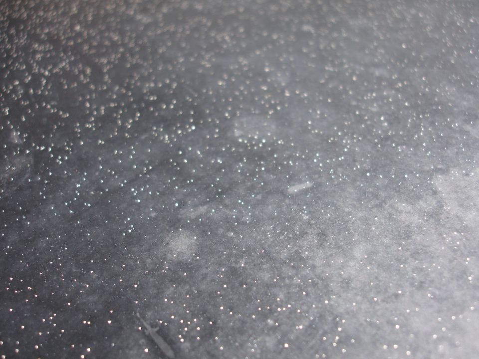 Gray textured surface with many small white specks, possibly ice crystals or glitter