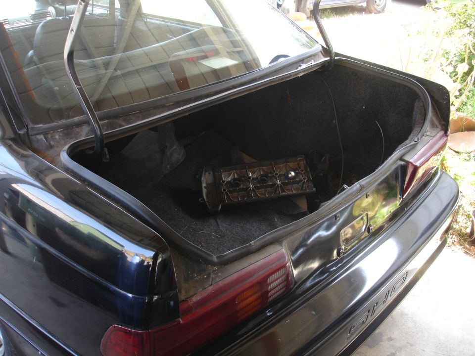 Open trunk of a black car with a disassembled engine part inside