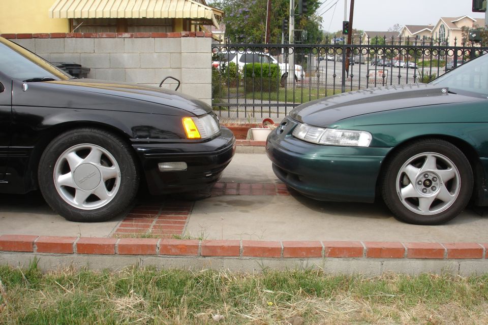 black sedan and green sedan parked nose to nose