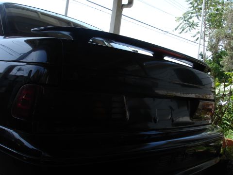 1991 Ford Taurus - Rear view of a black car with a spoiler and tinted taillights, showing distinctive body lines.