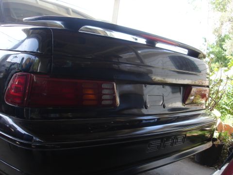 1991 Ford Taurus - The rear of a black car is visible, a spoiler and SHO badging.