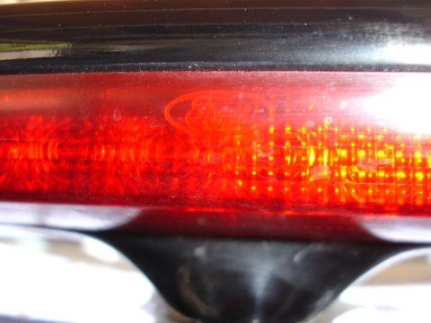 1991 Ford Taurus - Close-up of a red taillight assembly an embossed Ford logo.