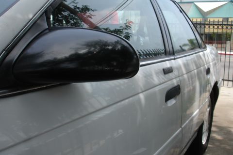 1992 Ford Taurus - The side profile of a white sedan is captured, highlighting its door handles and side mirror.