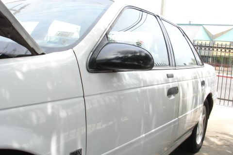 1992 Ford Taurus - A white sedan is parked outdoors with its hood open, revealing a 2000 registration sticker on the windshield.
