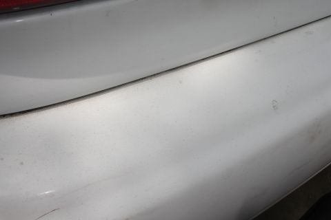 1992 Ford Taurus - Detail shot of a white vehicle's rear section, showing the bumper and a portion of the taillight.