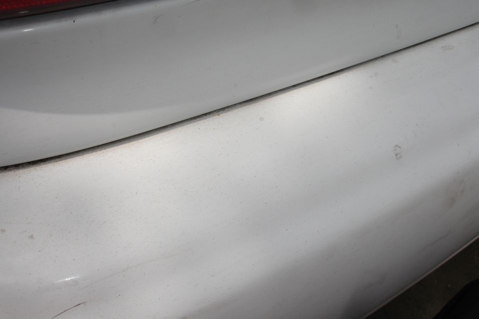 Close-up of a white car's rear bumper and part of a taillight