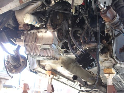 1992 Ford Taurus - Underside view of a vehicle's engine compartment and suspension components, supported by jack stands.