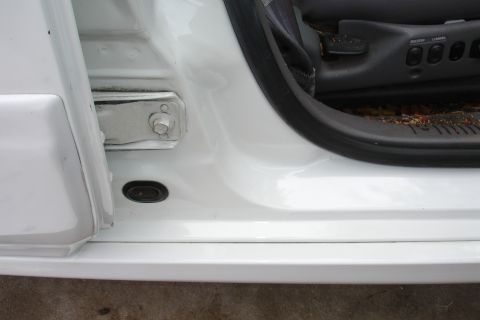 1992 Ford Taurus - Close-up of a white car's interior door jamb, revealing seat adjustment controls and the door hinge mechanism.