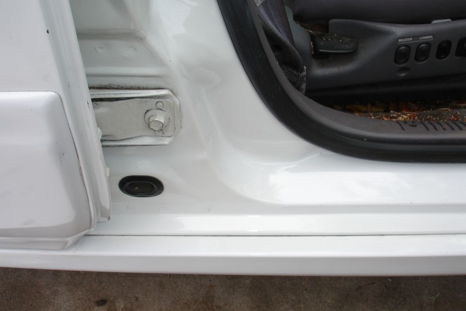 White car door jamb with visible seat controls and hinge