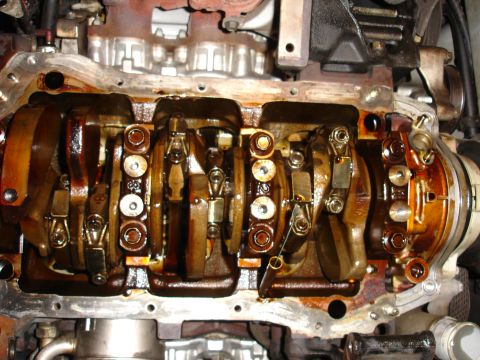 1992 Ford Taurus - Close-up view of an engine's internal components, showing the crankshaft and connecting rods coated in oil.