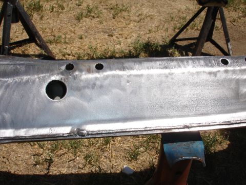 1992 Ford Taurus - A bare metal vehicle frame component is shown supported by jack stands outdoors.