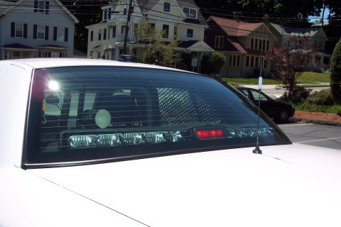 2001 Ford Crown Victoria - Rear view of a white vehicle, possibly a police car, with a light bar mounted above the rear window.