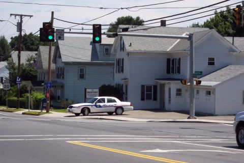 2001 Ford Crown Victoria - A white police car is parked on the side of the road in front of a building.