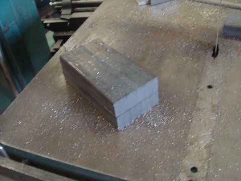 1996 Ford Bronco - Metal bars are stacked on a workbench covered in metal shavings.