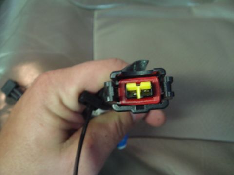 1996 Ford Bronco - A hand holds an electrical connector with red and yellow components, likely a vehicle part.