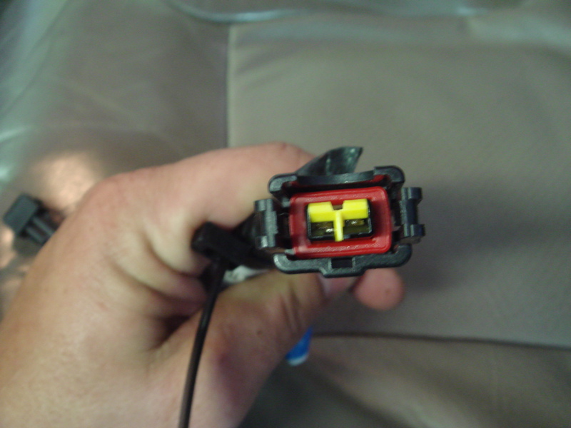 Hand holding a black and red electrical connector with yellow inserts