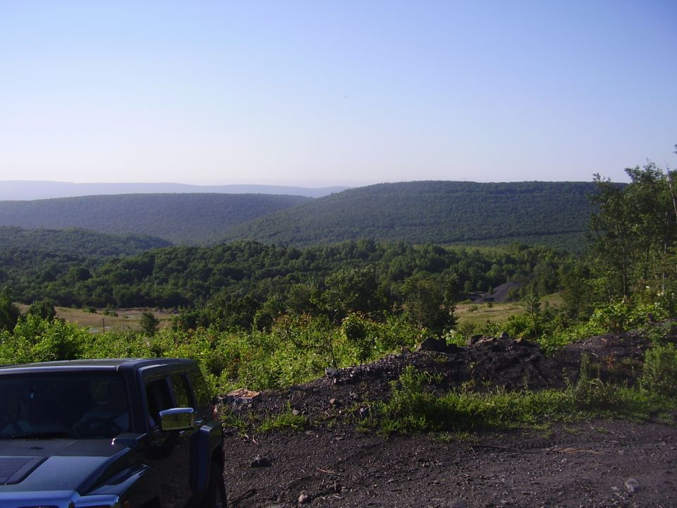 Forested mountain valley view with vehicle in foreground