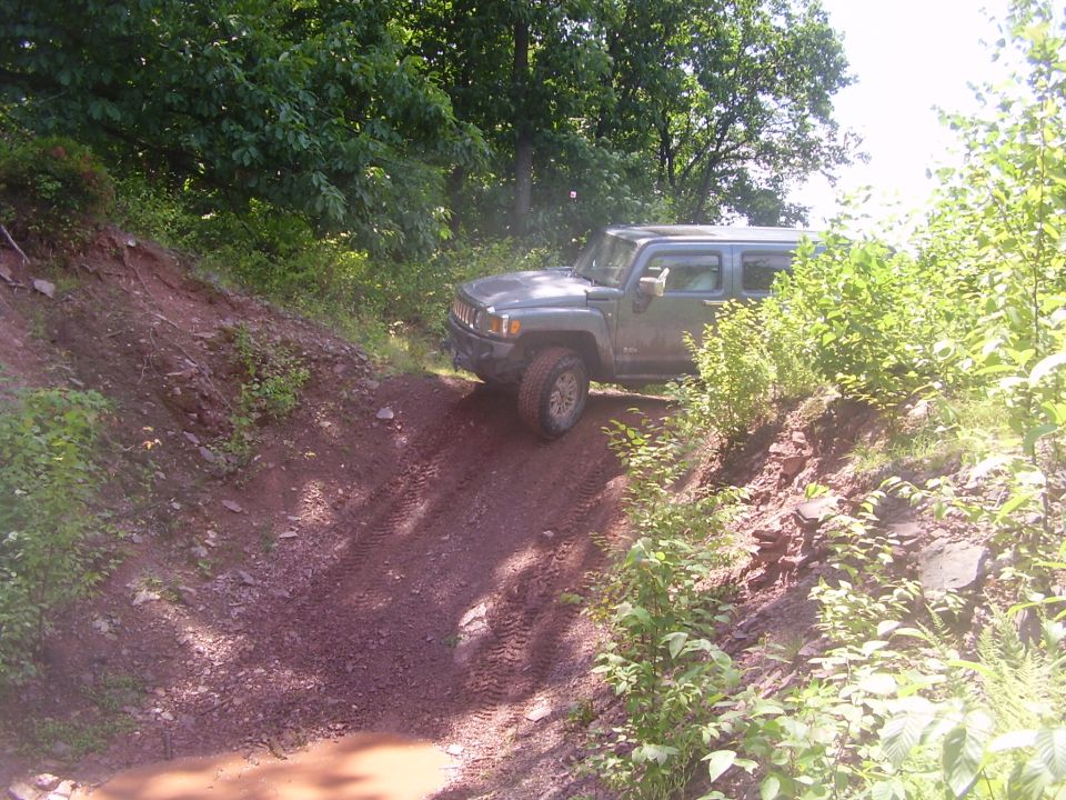 Gray Hummer H3 driving on a dirt trail with trees on either side