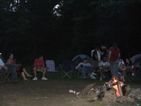 1991 Ford Probe - Campers gather around a fire under the dark sky, with tents set up nearby.