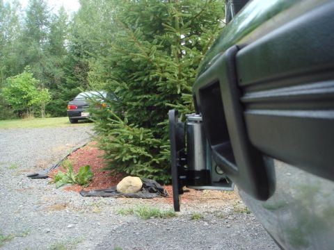 1996 Ford Bronco - Close-up of a winch installed on a vehicle's bumper, with another car visible in the distance.