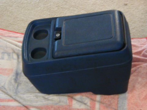 1986 Ford Bronco - This blue plastic center console features two cup holders and a locking storage compartment.