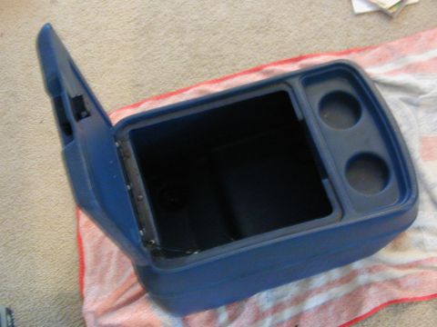 1986 Ford Bronco - This blue center console with an open lid and two cup holders is a part from a vehicle.