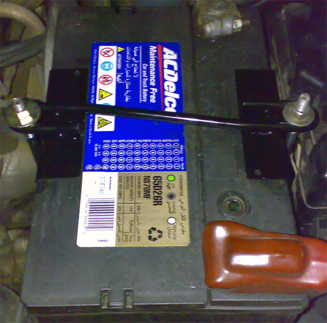ACDelco maintenance-free car battery secured by a black hold-down clamp bar