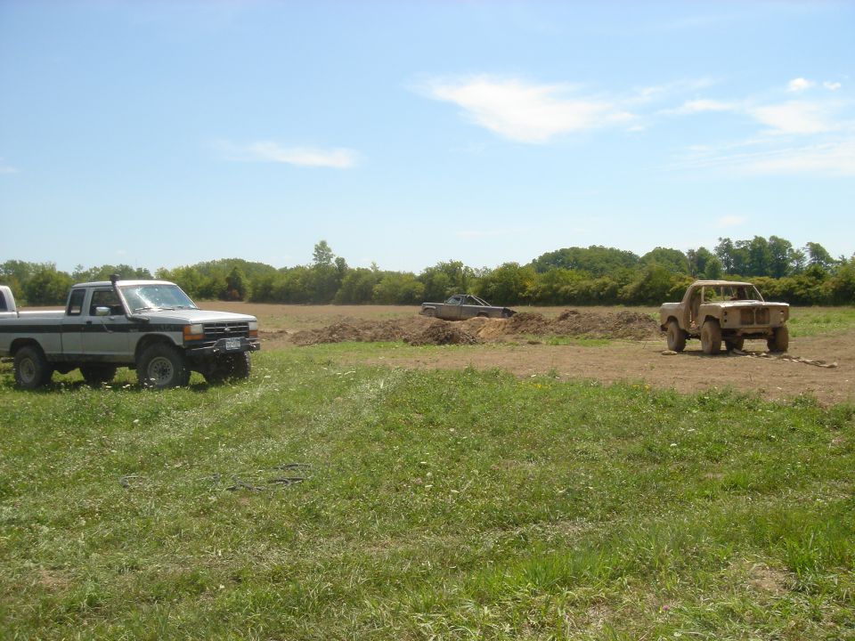 Three trucks in a field under a blue sky