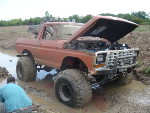 1979 Ford F-250 - Orange 1979 Ford F-250 off-road truck stuck in mud pit with another vehicle behind it.